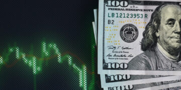 A stack of 100-dollar bills lies in the lower right corner beside a digital screen showing a green, declining stock market graph on a dark background, highlighting the potential benefits of Dollar-Cost Averaging during downturns. | ZIIMP