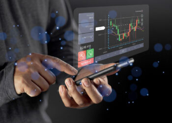 A person uses a smartphone displaying a floating digital interface with stock market charts, buy and sell buttons, and financial data against a dark background with blue light effects. | ZIIMP